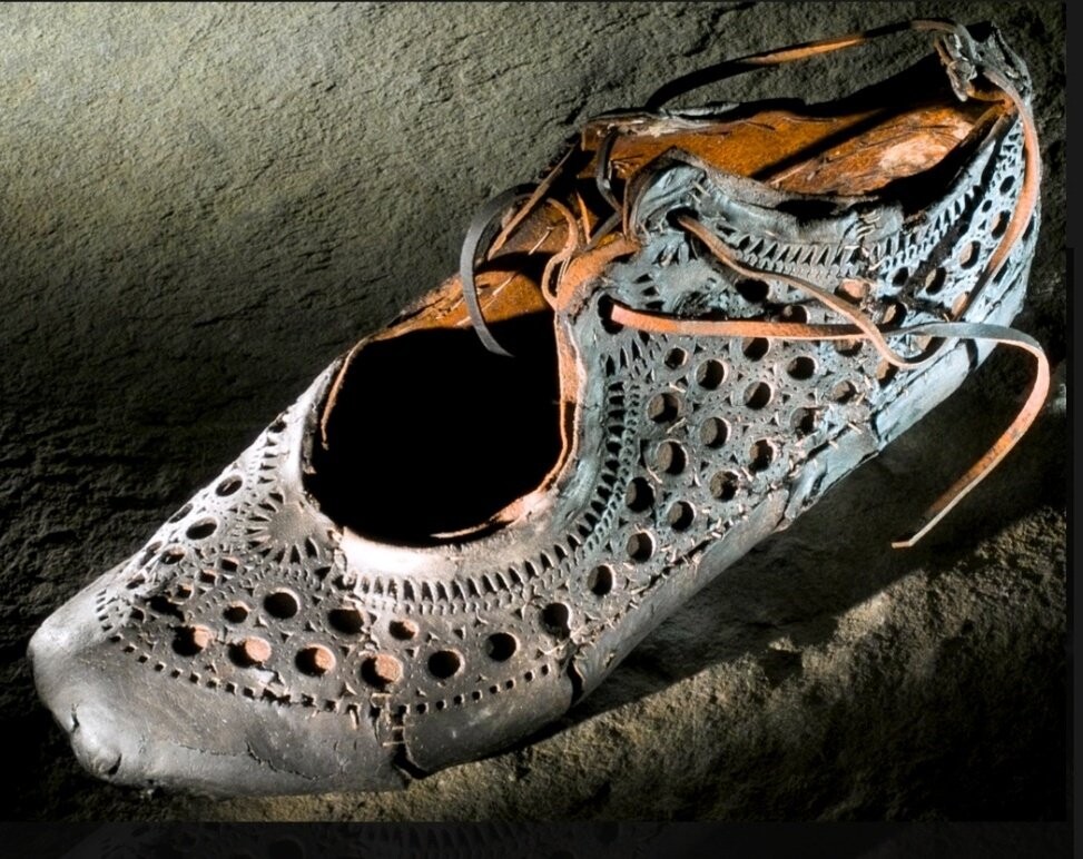 The picture shows a single leather shoe with a decorative pattern of holes of different sizes and shapes (e.g circles, triangles).