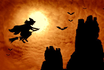 Auf einem Besen fliegende Hexe vor gelbem Mond und rotorangem Himmel, rechts oben 4 Fledermäuse. rechts unten schwarze Felsen