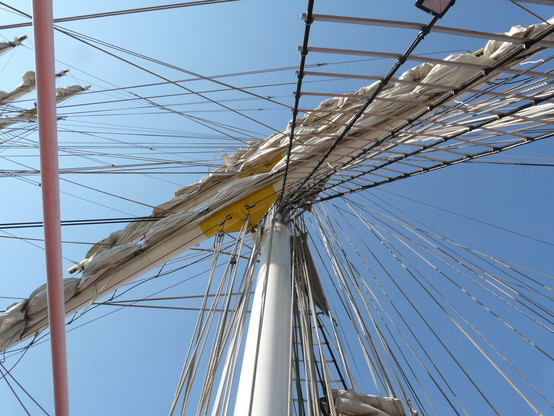Takelage und eingerolltes Segel aus der Höhe fotografiert bei strahlend blauem Himmel