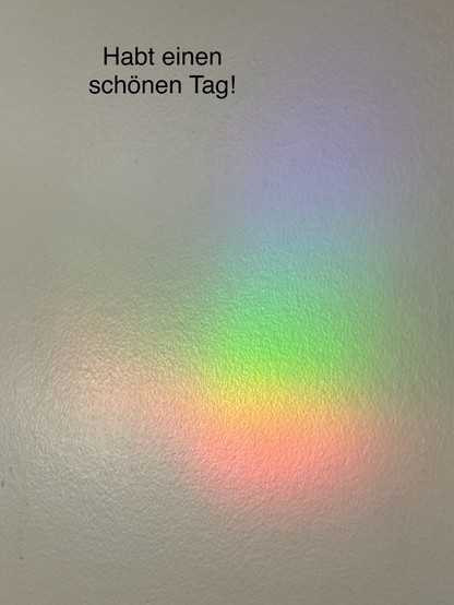 Wall with a rainbow reflection and German text reading 
