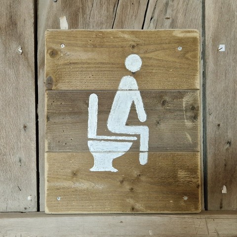 Auf Toilette sitzende Person. Weisse Farbe auf Holz.