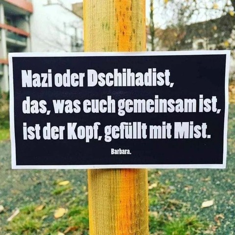 Ein Schild an einem Holzpfahl in einer Wohngegend. Auf diesem steht:

Nazi oder Dschihadist, das, was euch gemeinsam ist, ist der Kopf, gefüllt mit Mist.

Barbara.