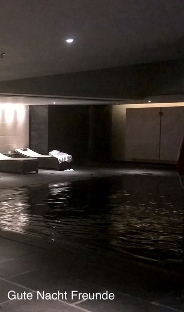 A dimly lit indoor pool area with lounge chairs and a towel. Text reads 