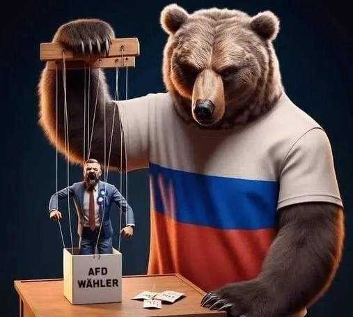 Ein russischer Bär macht einen Puppenspieler und spielt mit Fäden an einer Puppe stehend im Karton. Auf dem Karton steht: AFD WÄHLER