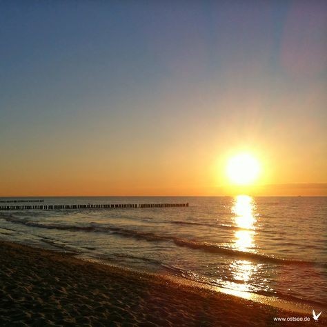 Abendsonne über dem ruhigen Meer, im Vordergrund Strand