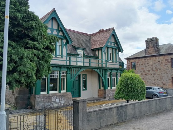 Wohnhaus in Invergordon. Ein cremeweißes Langhaus mit zwei quer stehenden bedachten Erkern.   Das Haus ist mit grünen Streben verziert und erinnert daher an Fachwerk.