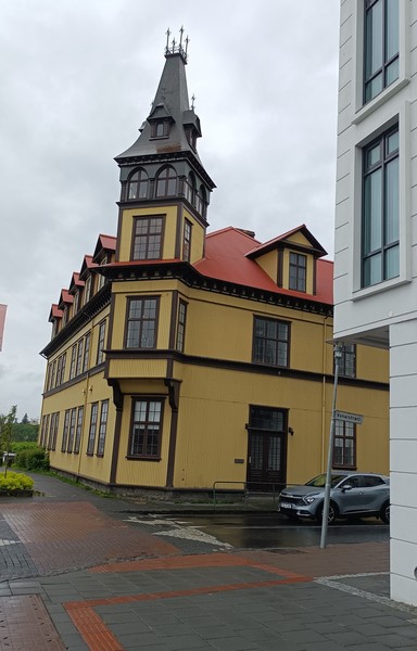 Altes Kirchengebäude in Reykjavik. Das dreistöckige Gebäude ist gelb gestrichen und hat auf der Ecke einen kleinen Turm. 