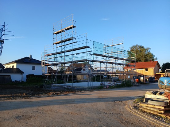 ein Baugerüst wurde auf einer betonierten Bodenplatte montiert. In den nächsten Tagen wird hier das nächste Holzhaus in vorgefertigter Modulbauweise aufgerichtet werden