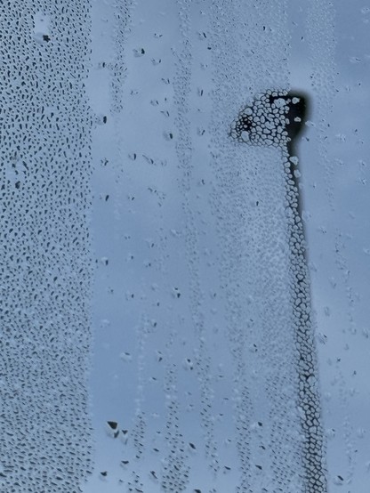 A close-up of a foggy window, showcasing droplets of water and a blurred silhouette of a lamppost in the background against a gray sky.

Eine Nahaufnahme eines nebligen Fensters mit Wassertropfen und einer verschwommenen Silhouette eines Laternenpfahls im Hintergrund vor einem grauen Himmel.