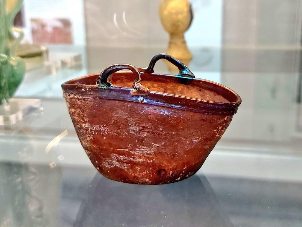 The picture shows a vessel in the shape of a two handled basket of brown colour.