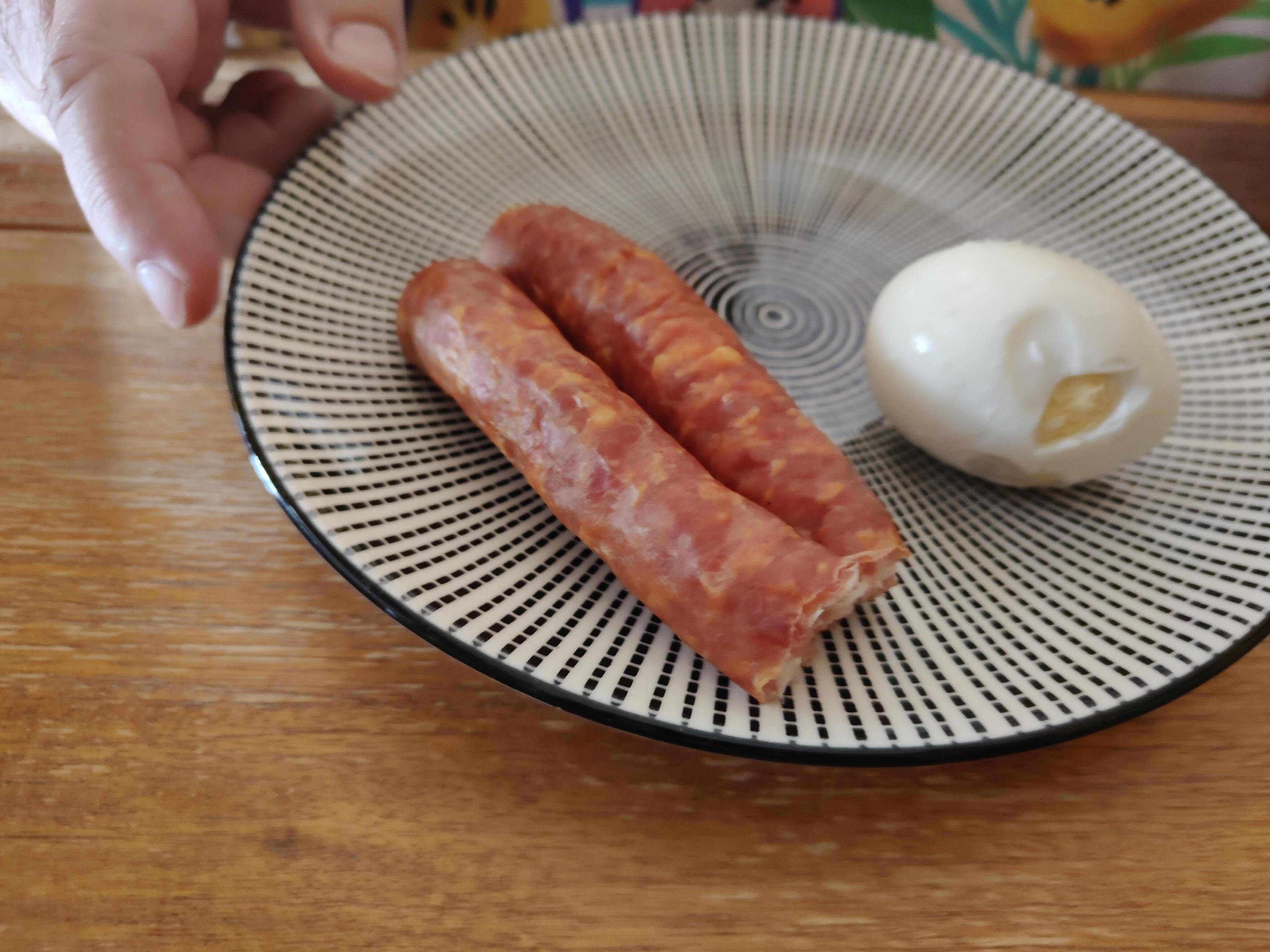 In zwei Teile gebrochener Rohesser "Westfälische Art" neben einem hartgekochten Ei auf einem Frühstücksteller.